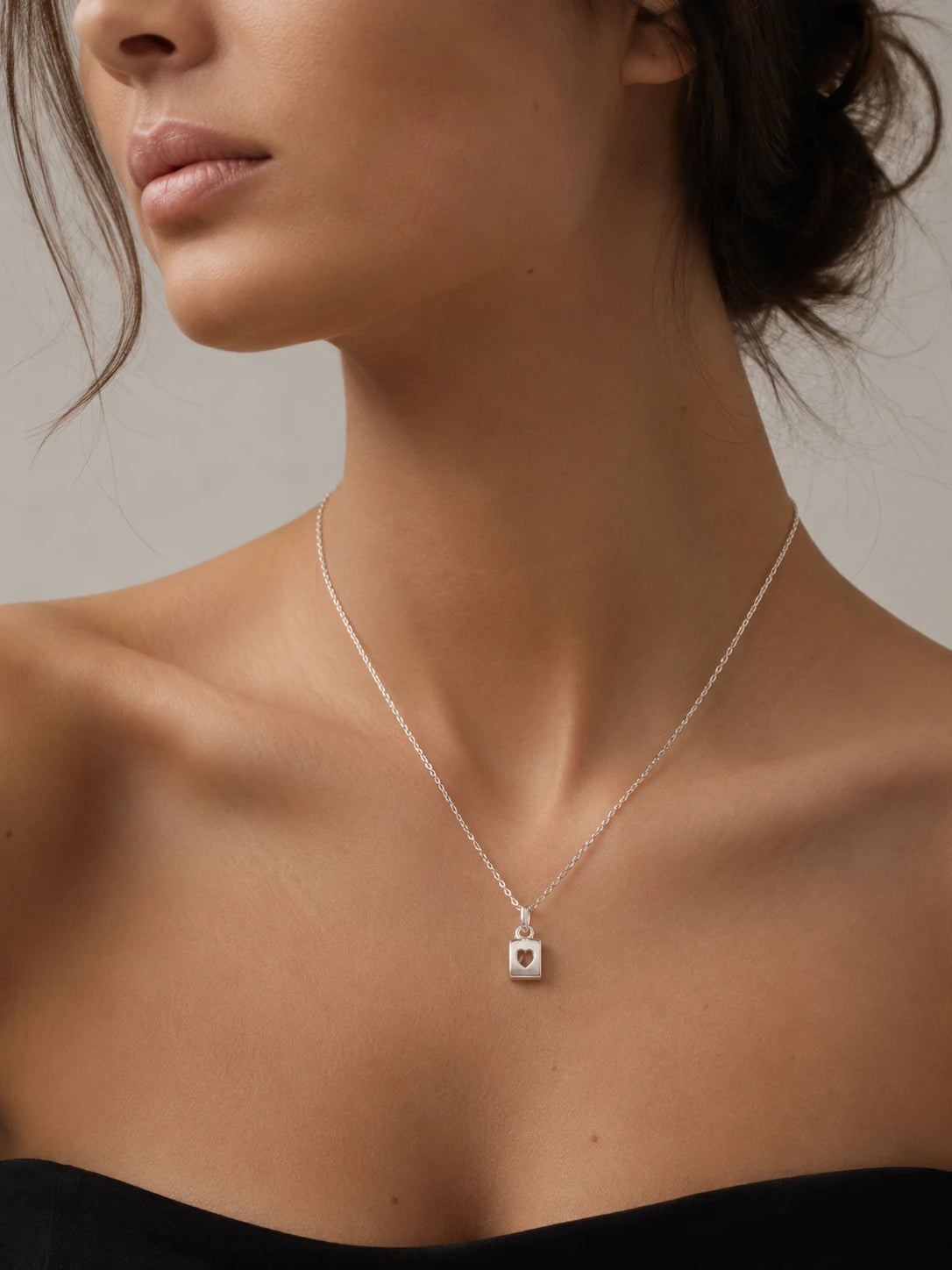 Necklace with a heart pendant worn by a model against a neutral background