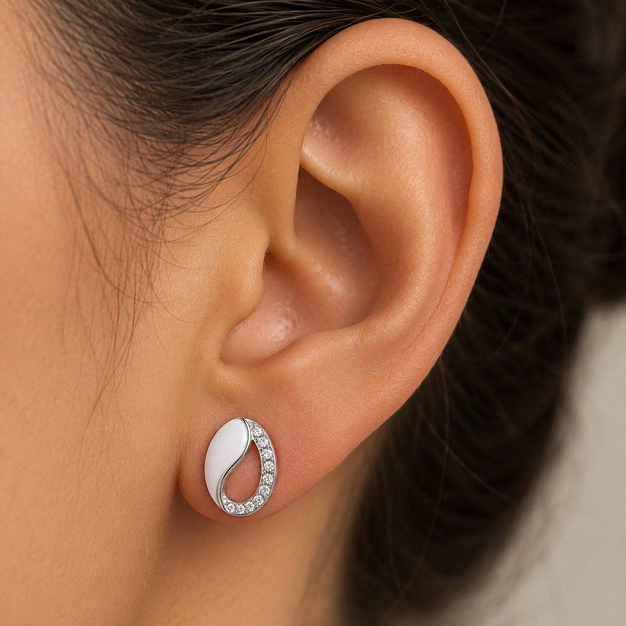 Close-up of an ear wearing a silver earring with a blurred background