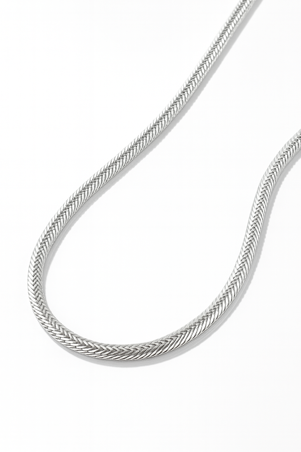 Close-up of a person wearing a thin silver chain necklace against a neutral background